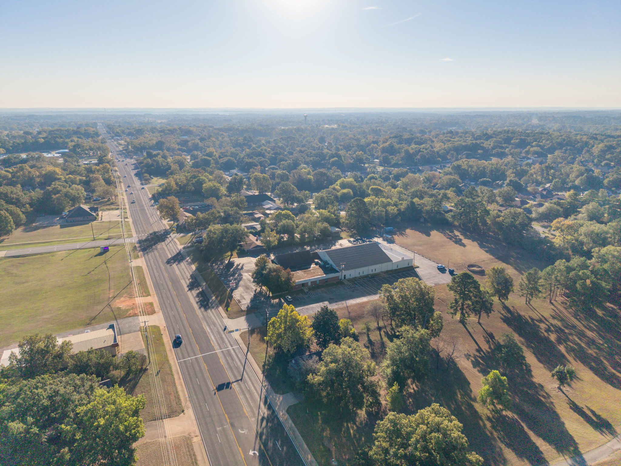 Aerial view along W. Main Street in Whitehouse, Texas, showing roadside properties, mature trees and nearby athletic fields.