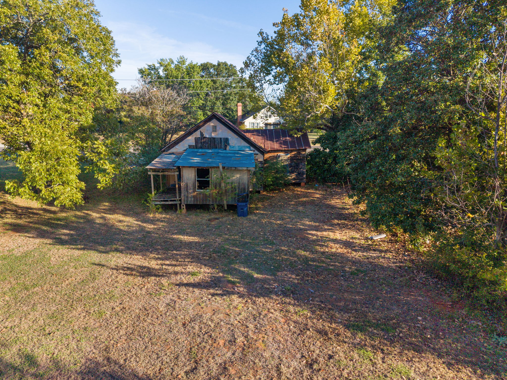 Existing house surrounded by mature trees and open yard at 409 W. Main Street in Whitehouse, Texas.