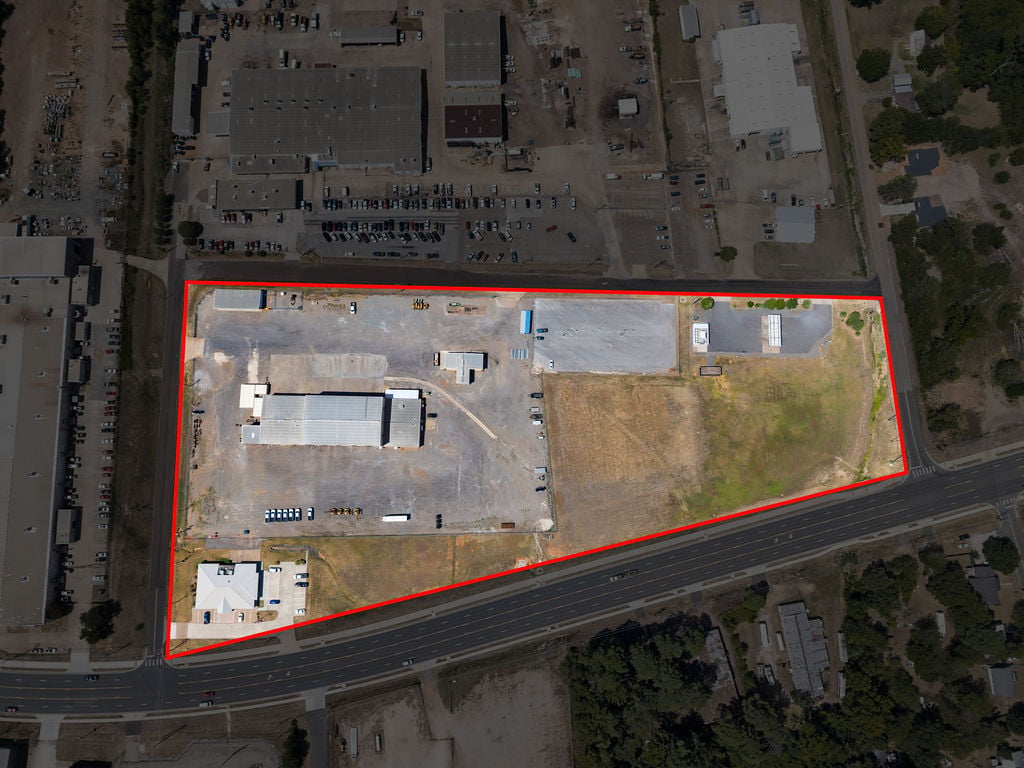 Overhead aerial of the main industrial site with shop buildings, paved yard and fenced perimeter outlined in red.