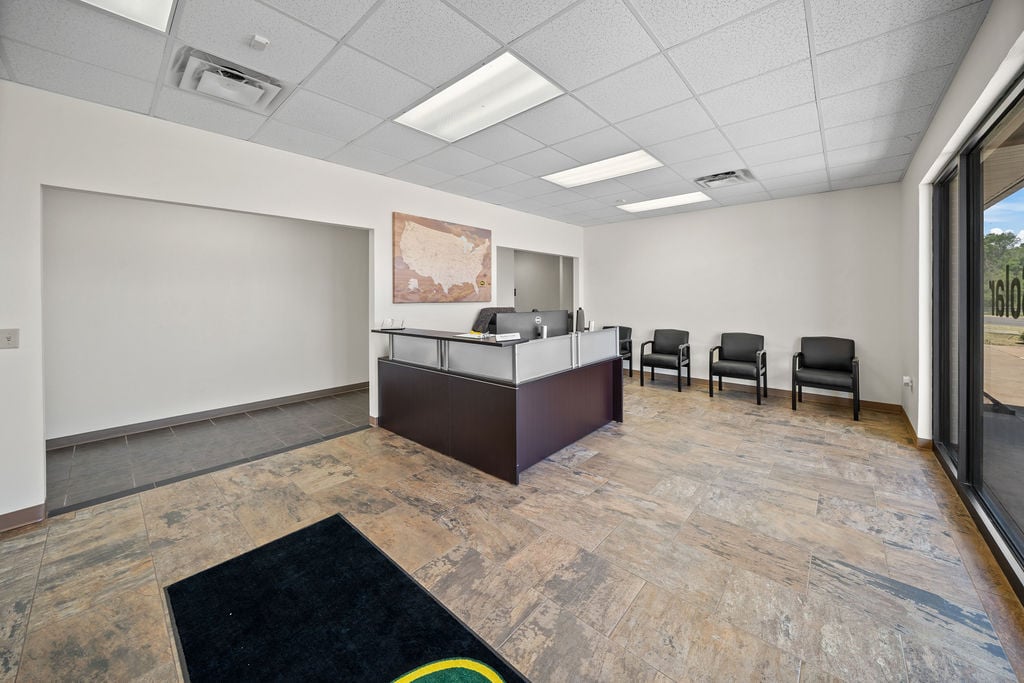 Office reception area with a front desk, waiting chairs and tile flooring.