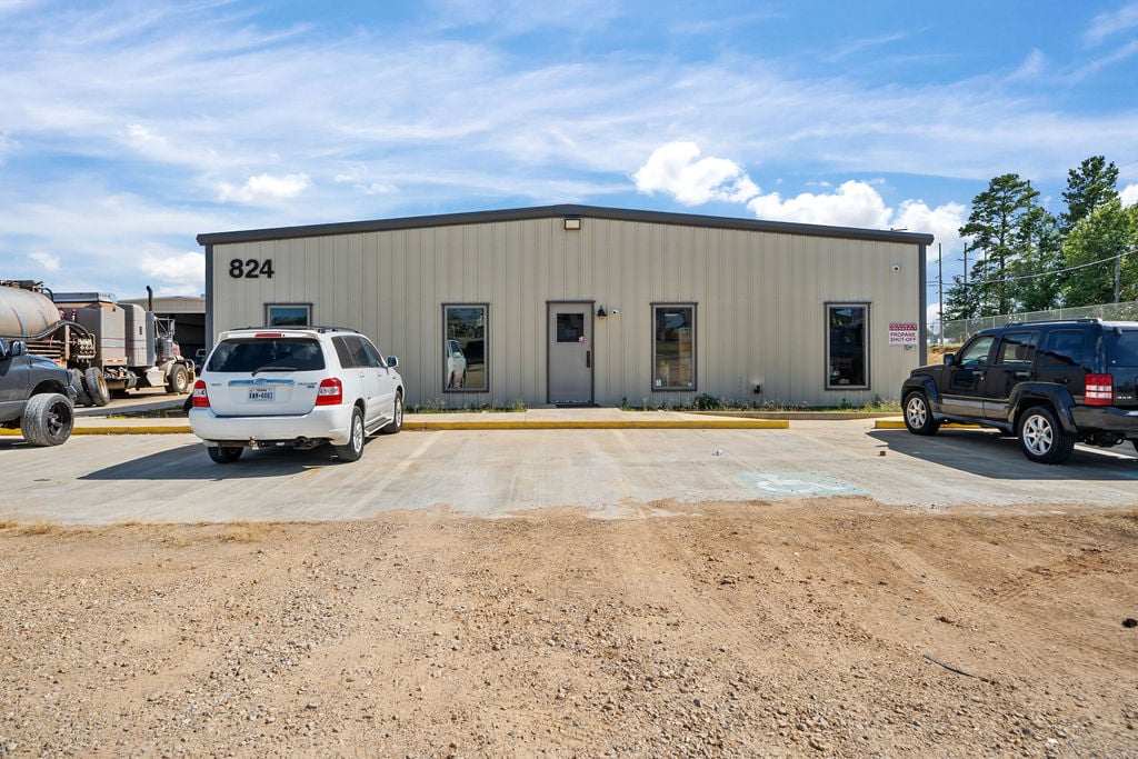 Single-story metal industrial building numbered 824 with a striped concrete parking lot.