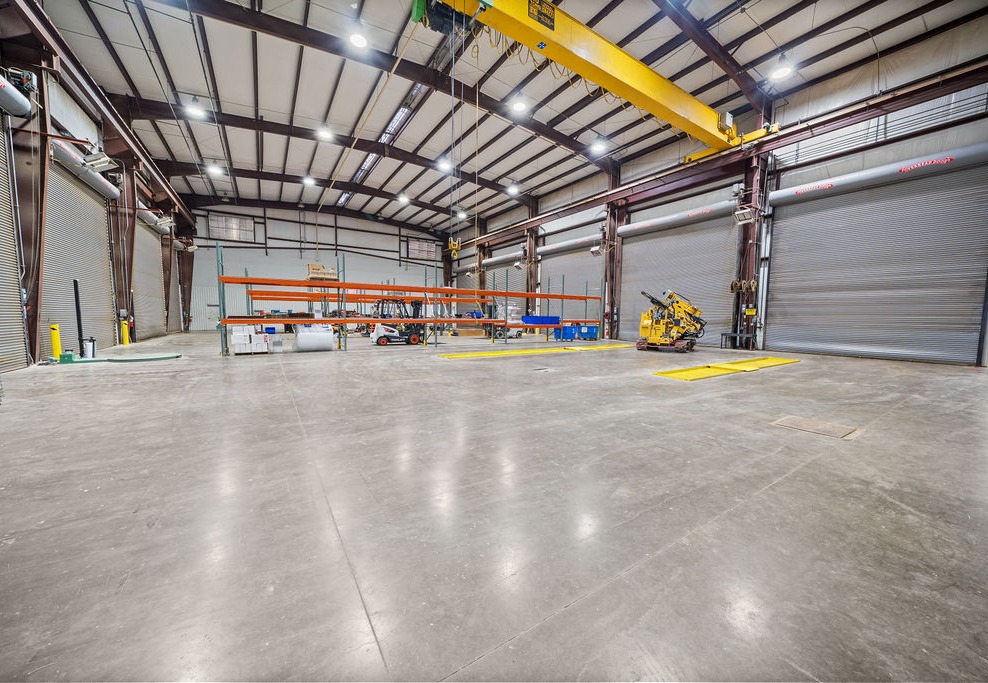 Interior of the industrial shop with a yellow overhead bridge crane, high clear-height steel framing and roll-up doors.