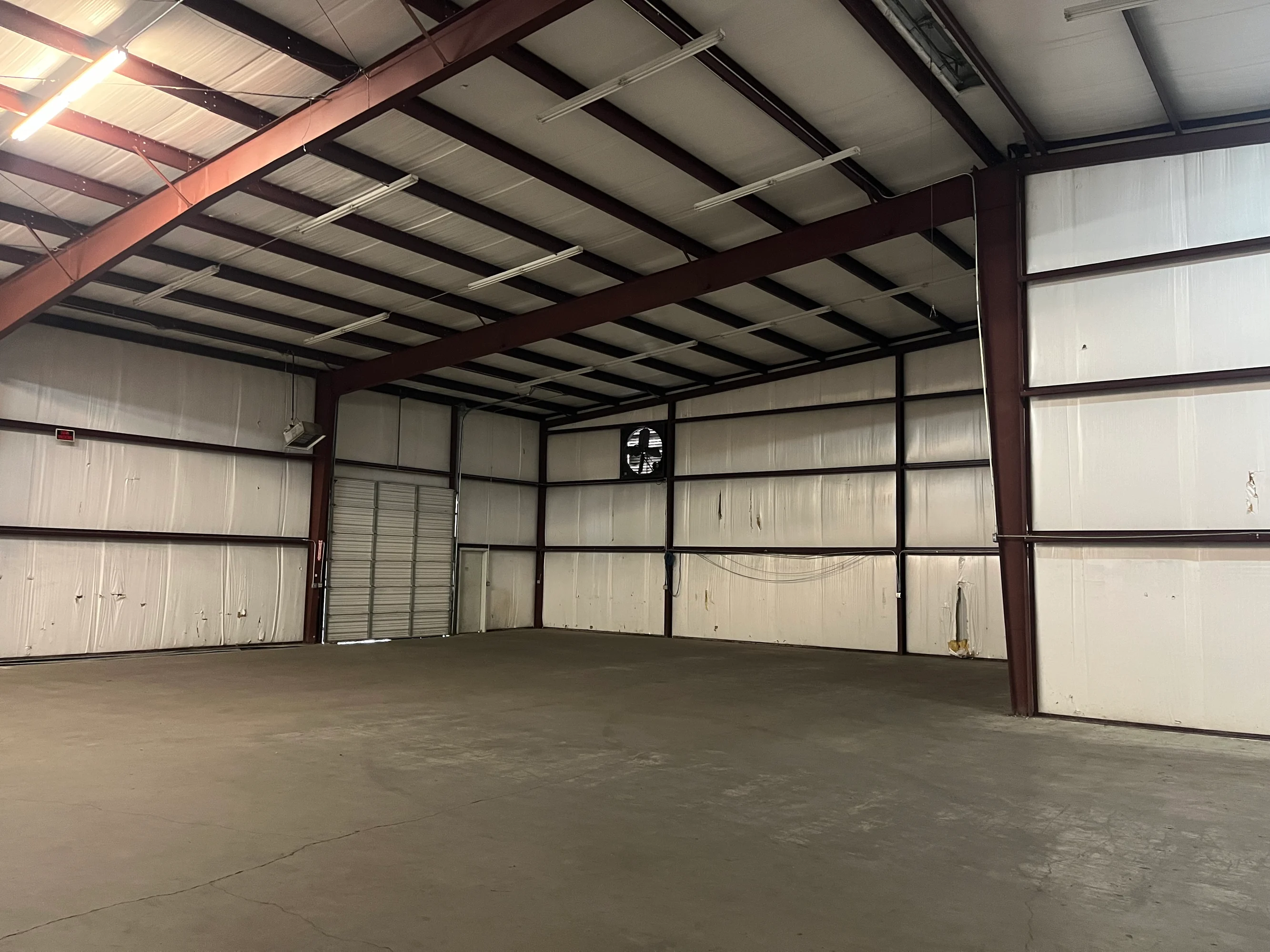 Open warehouse bay with high clear ceiling and wall exhaust fan at 13186 TX-110 in Tyler, Texas.