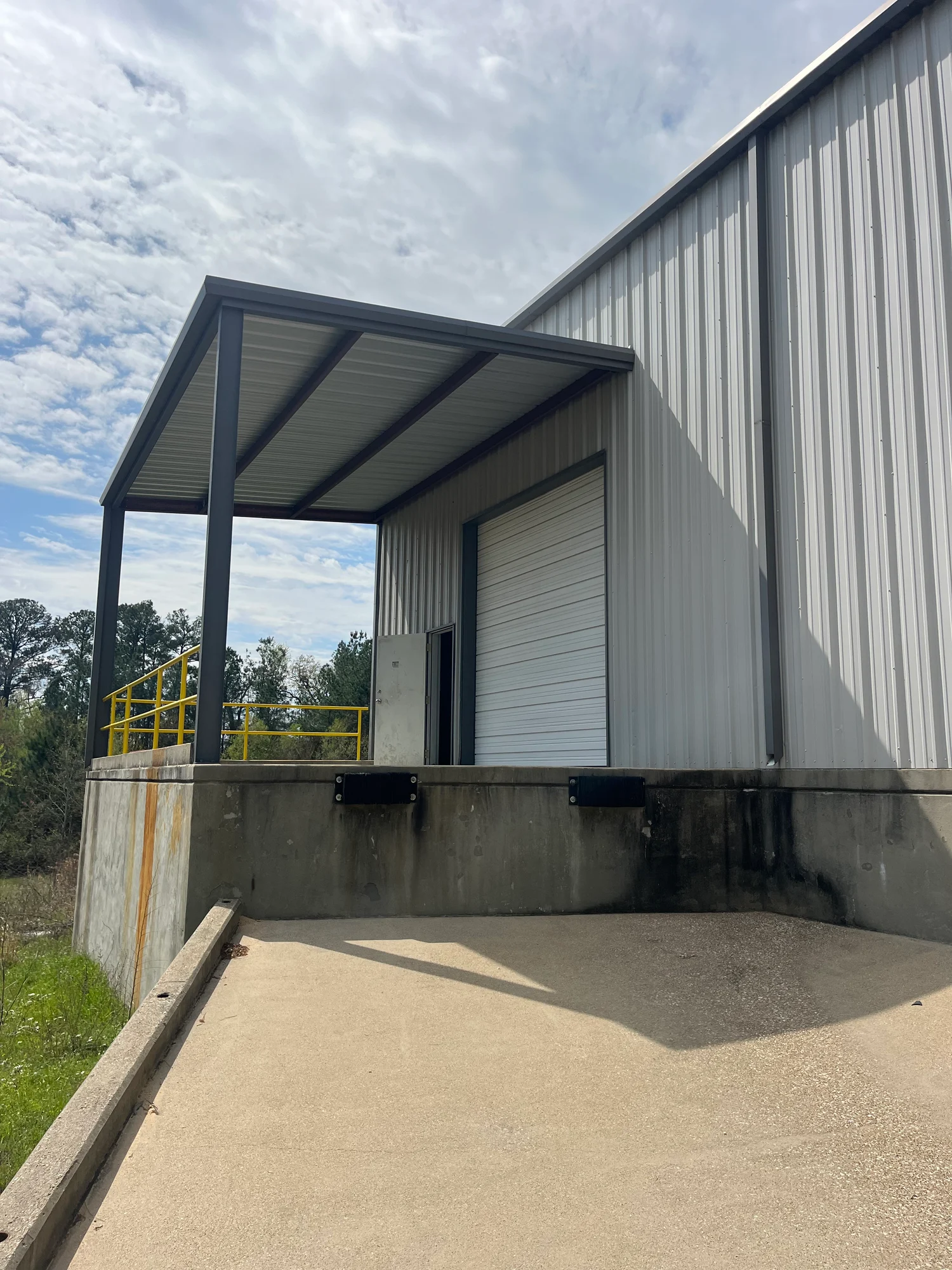 Warehouse bay with two roll-up doors and hanging unit heater at 13186 TX-110 in Tyler, Texas.