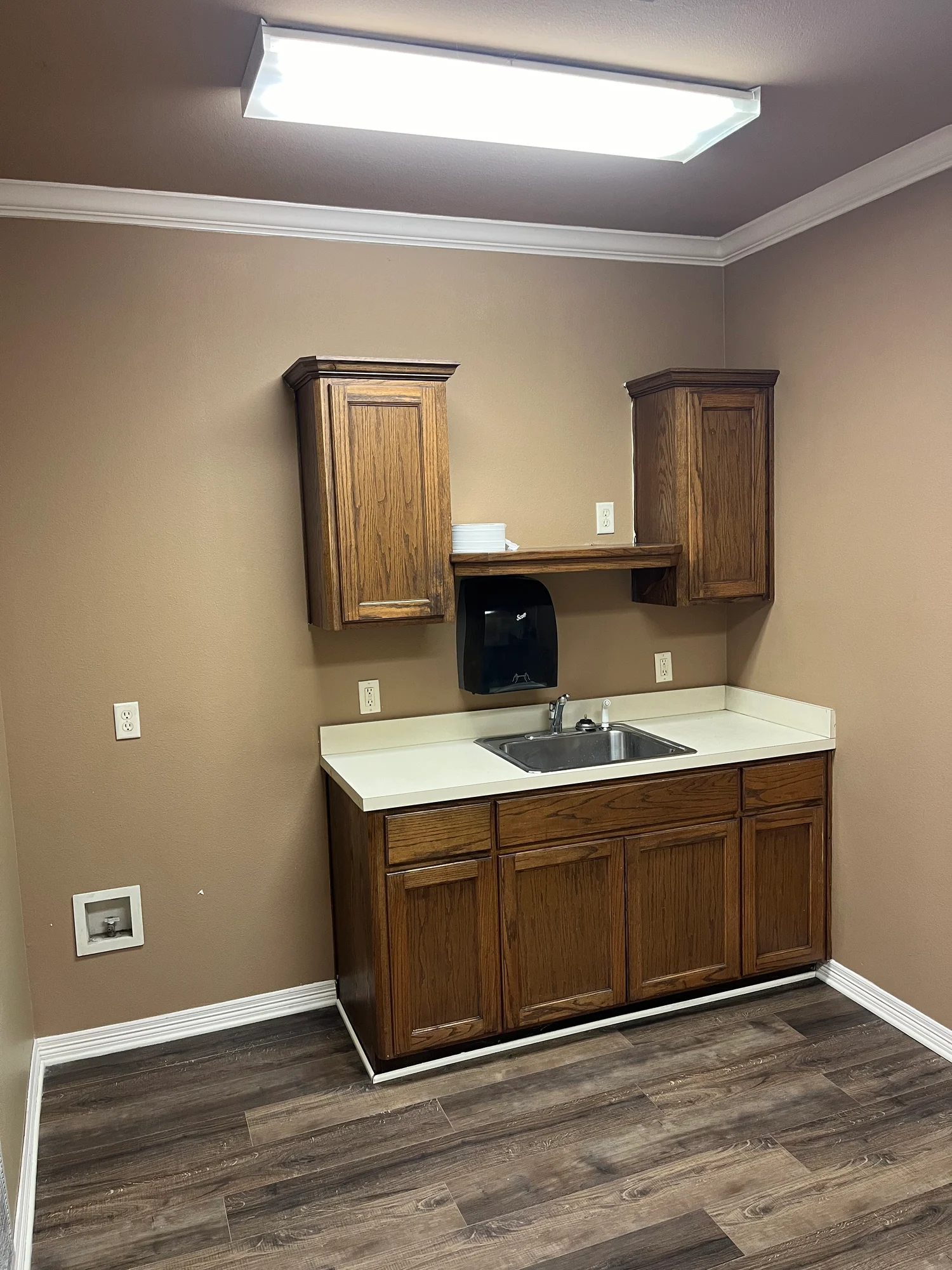 Kitchen break room with wood cabinets, stainless sink, and paper-towel dispenser at Highway 110 Industrial in Tyler, Texas.
