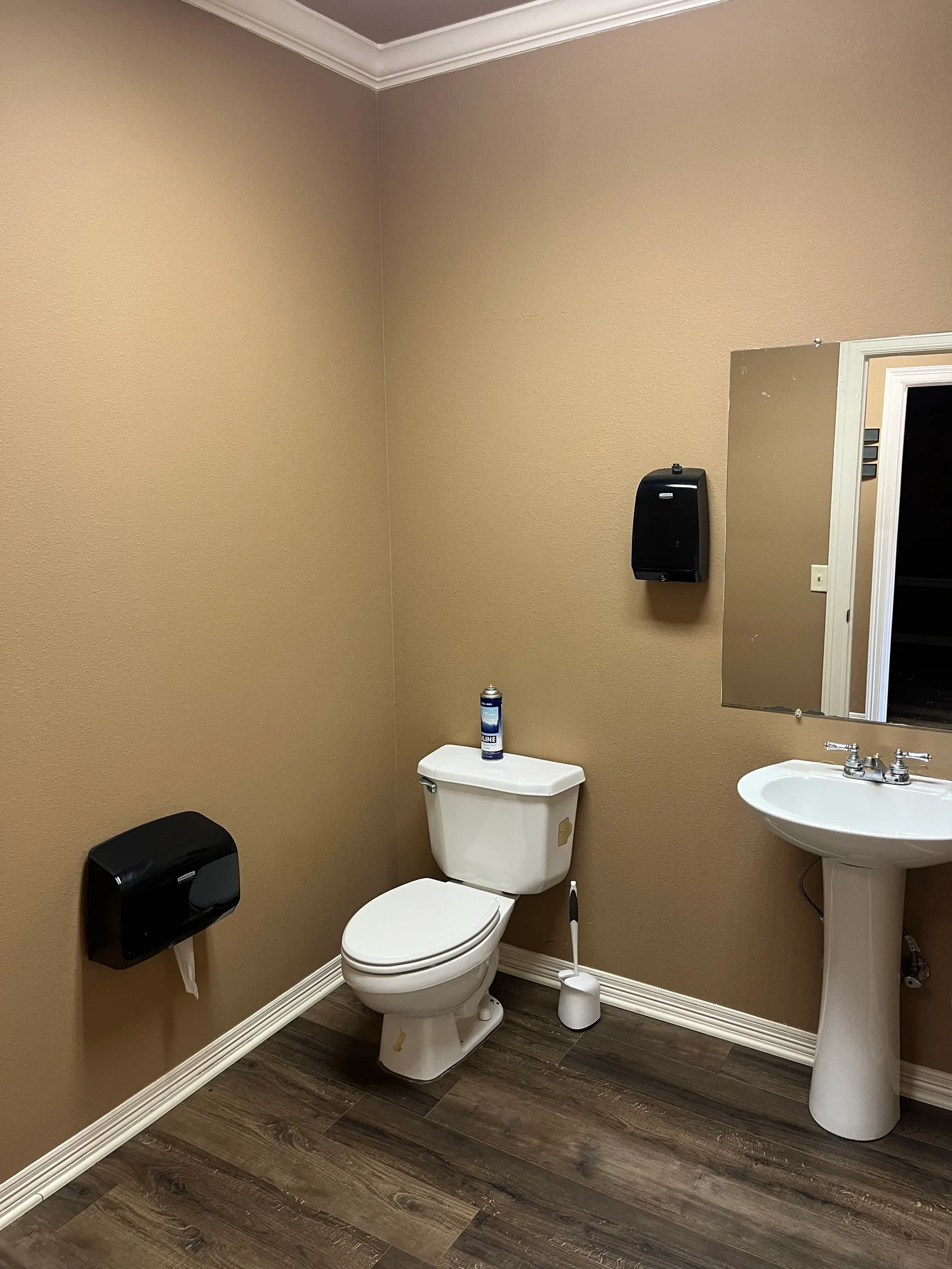 Office restroom with pedestal sink, toilet, mirror, and wall dispensers at 13186 TX-110 in Tyler, Texas.