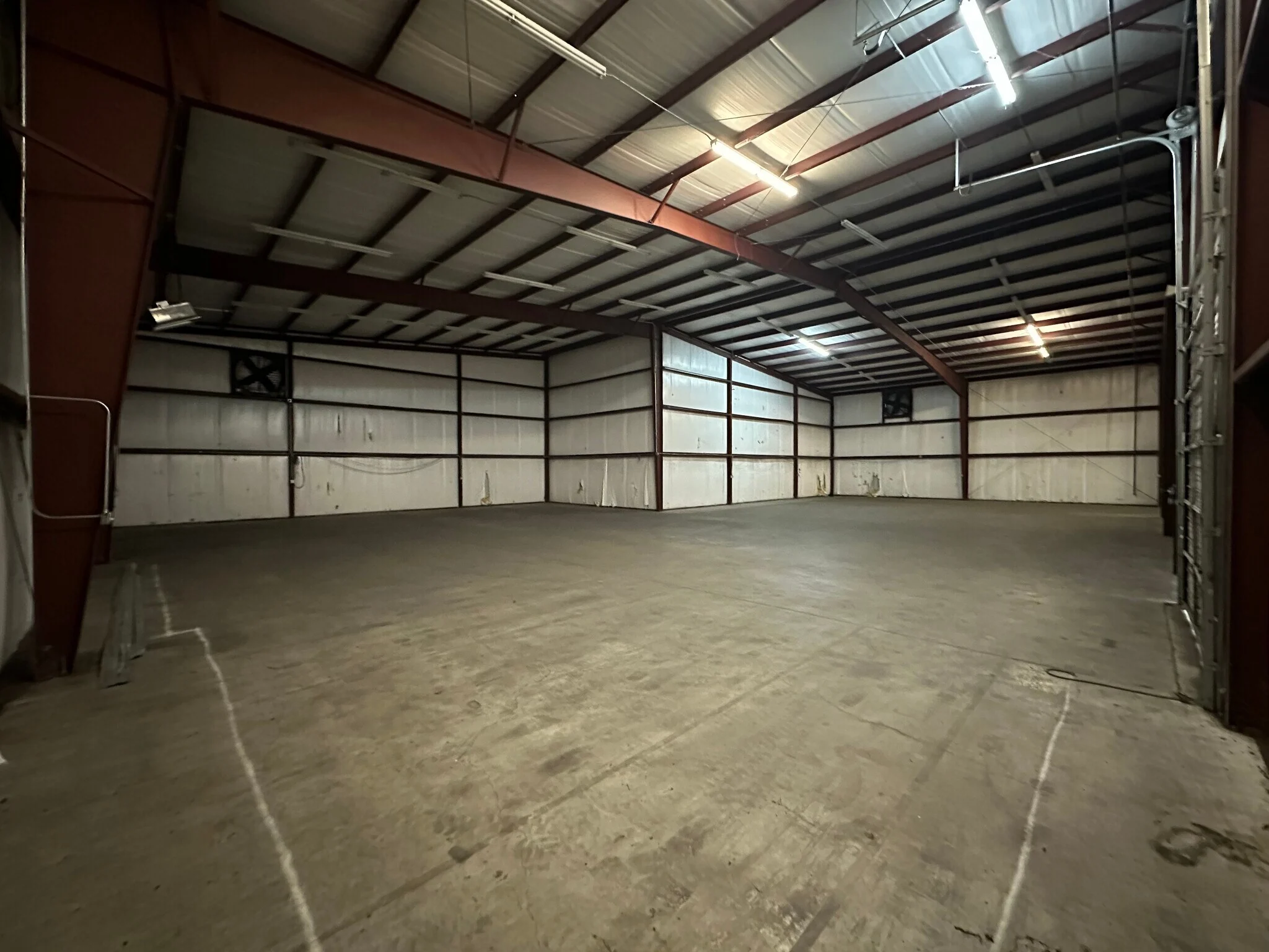 Large dark warehouse interior with exhaust fans and expansive concrete floor at 13186 TX-110 in Tyler, Texas.