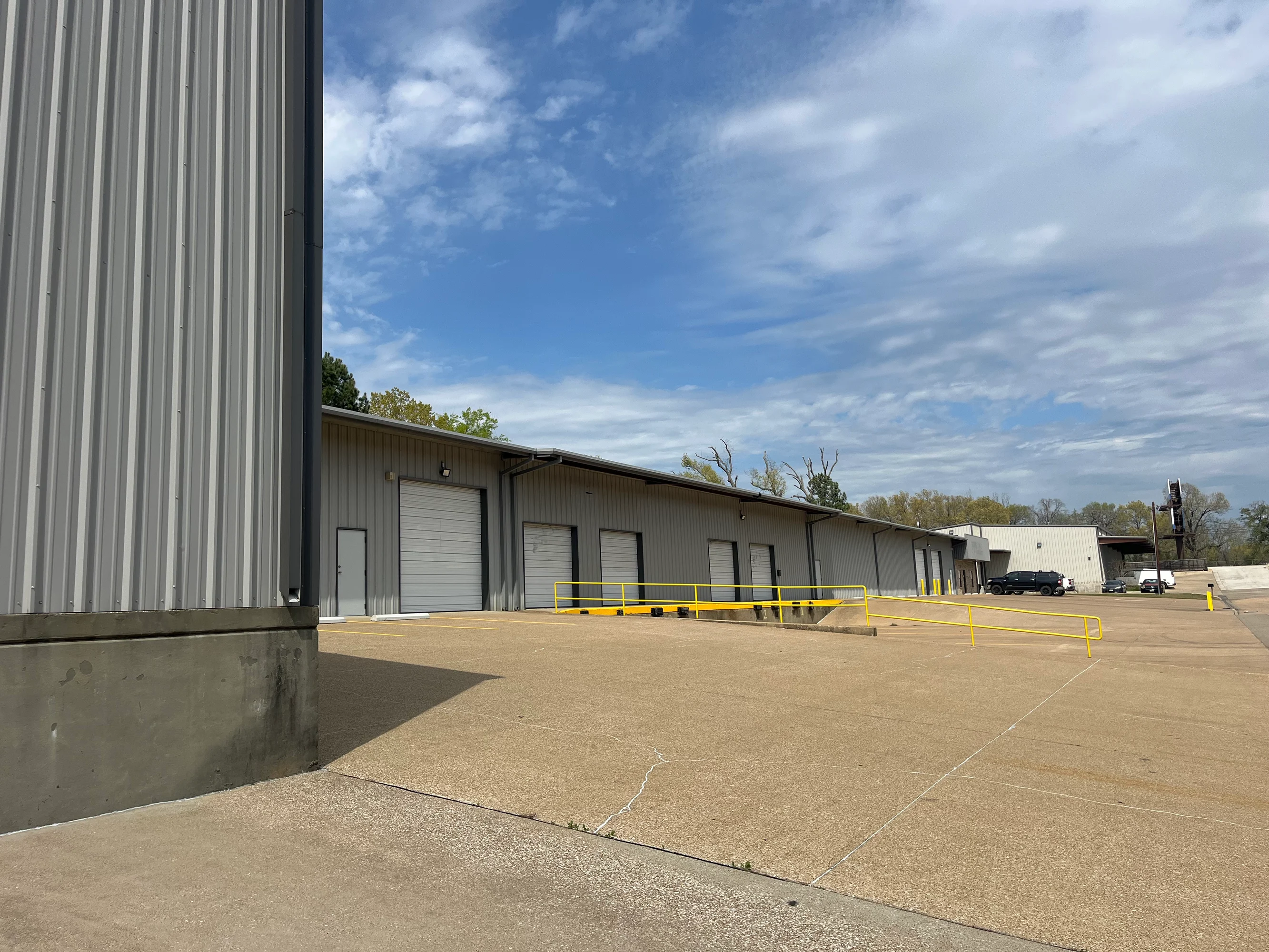Exterior grade-level and dock-high loading doors along the building with yellow railings at Highway 110 Industrial in Tyler, Texas.
