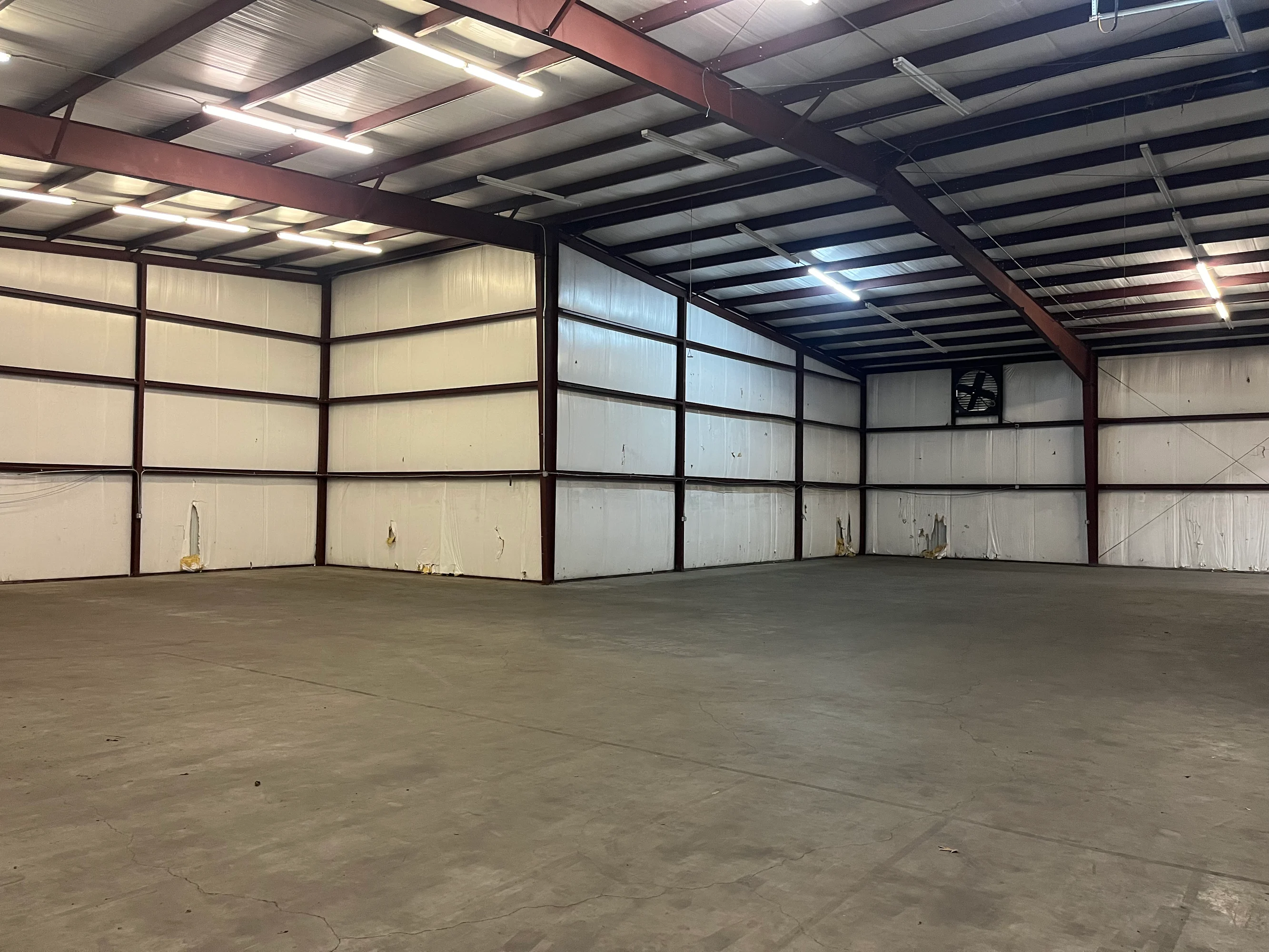 Cavernous empty warehouse bay under exposed steel structure and industrial lighting at Highway 110 Industrial in Tyler, Texas.