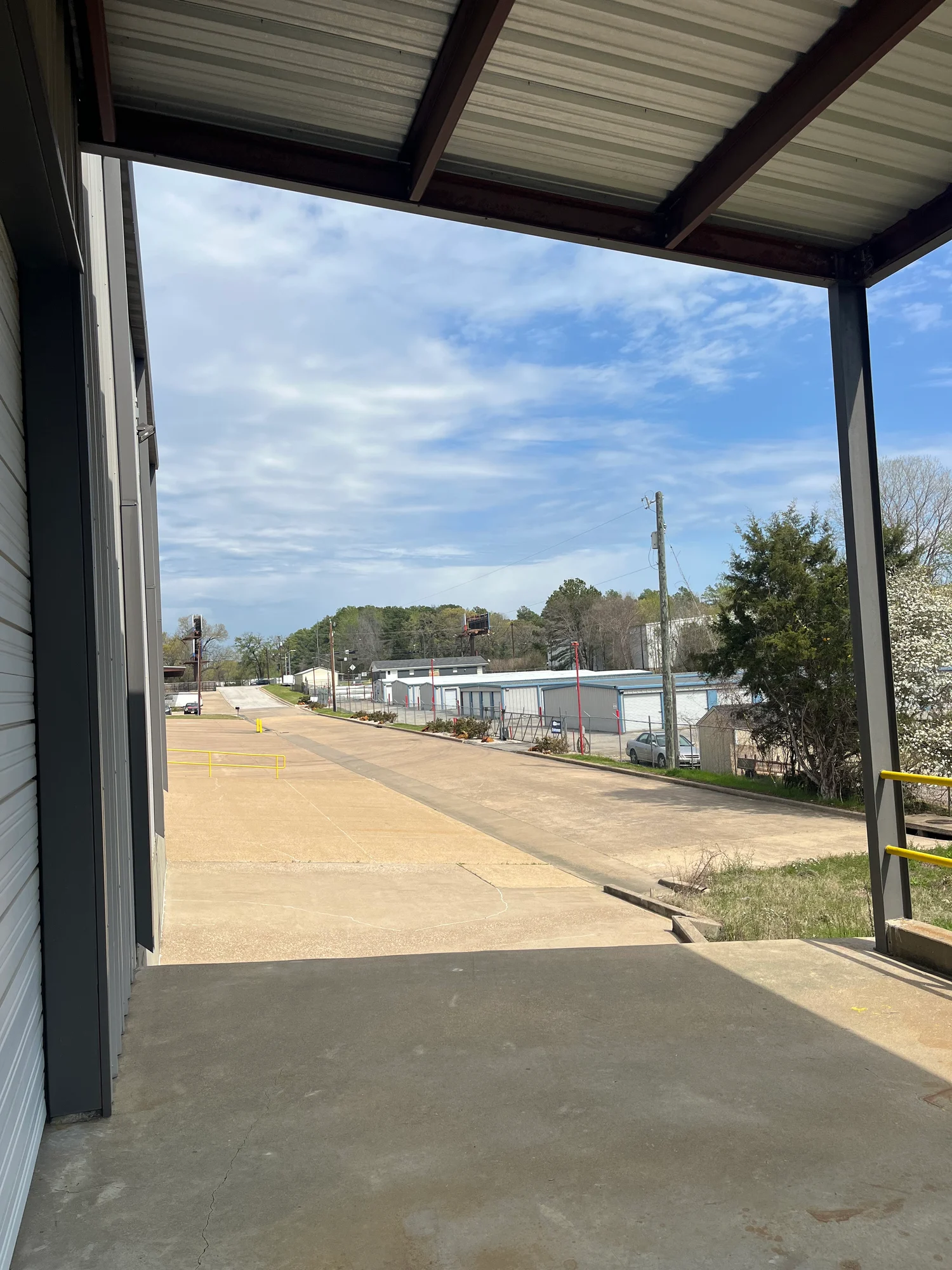 View from the covered loading dock toward the street and neighboring storage buildings at 13186 TX-110 in Tyler, Texas.